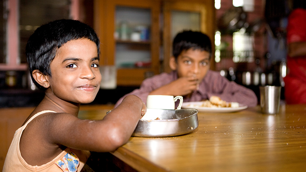 Portrait of a boy eating rice, another boy in the background